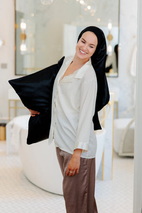 Nainen jolla on sylissään silkkinen tyyny ja päässään satiinibonnet